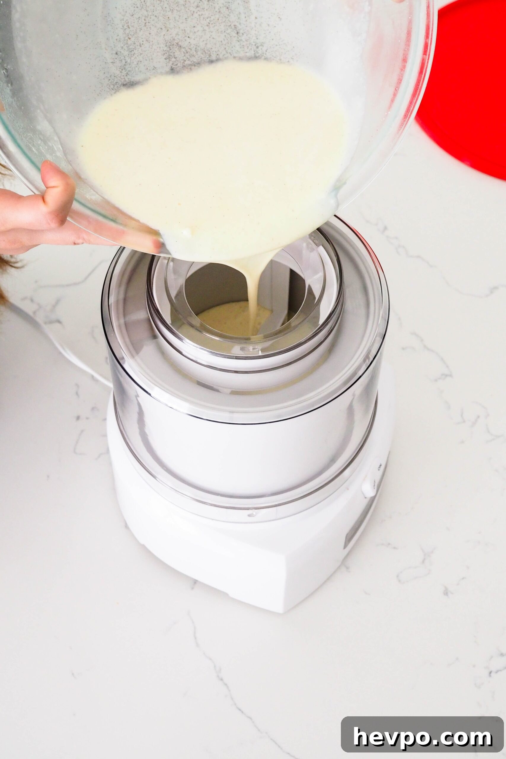 Homemade French Vanilla Ice Cream Recipe – Creamy & Classic 12 Two hands pour French vanilla ice cream base into an ice cream maker.
