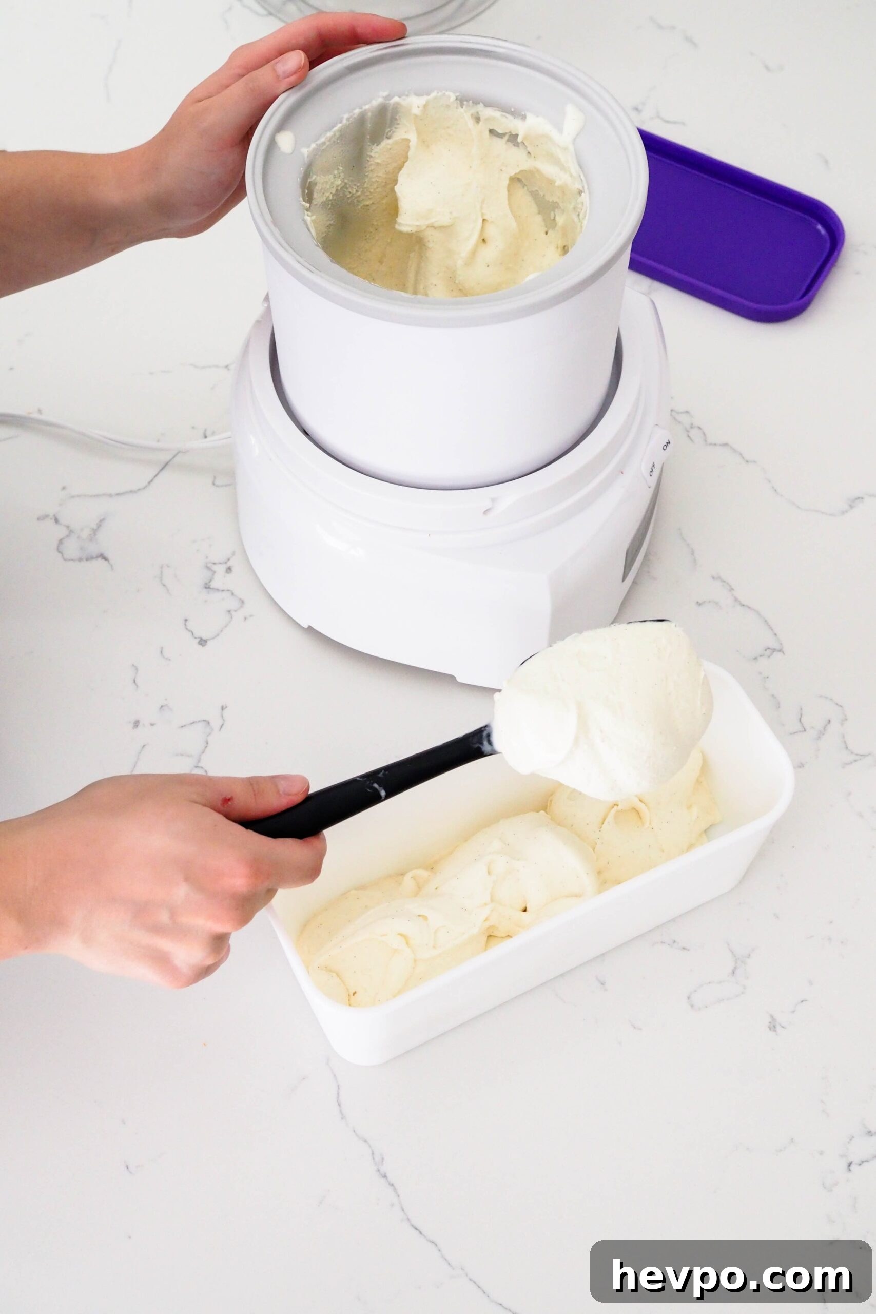 Homemade French Vanilla Ice Cream Recipe – Creamy & Classic 13 A hand scoops ice cream out of an ice cream maker canister and into a rectangular container.
