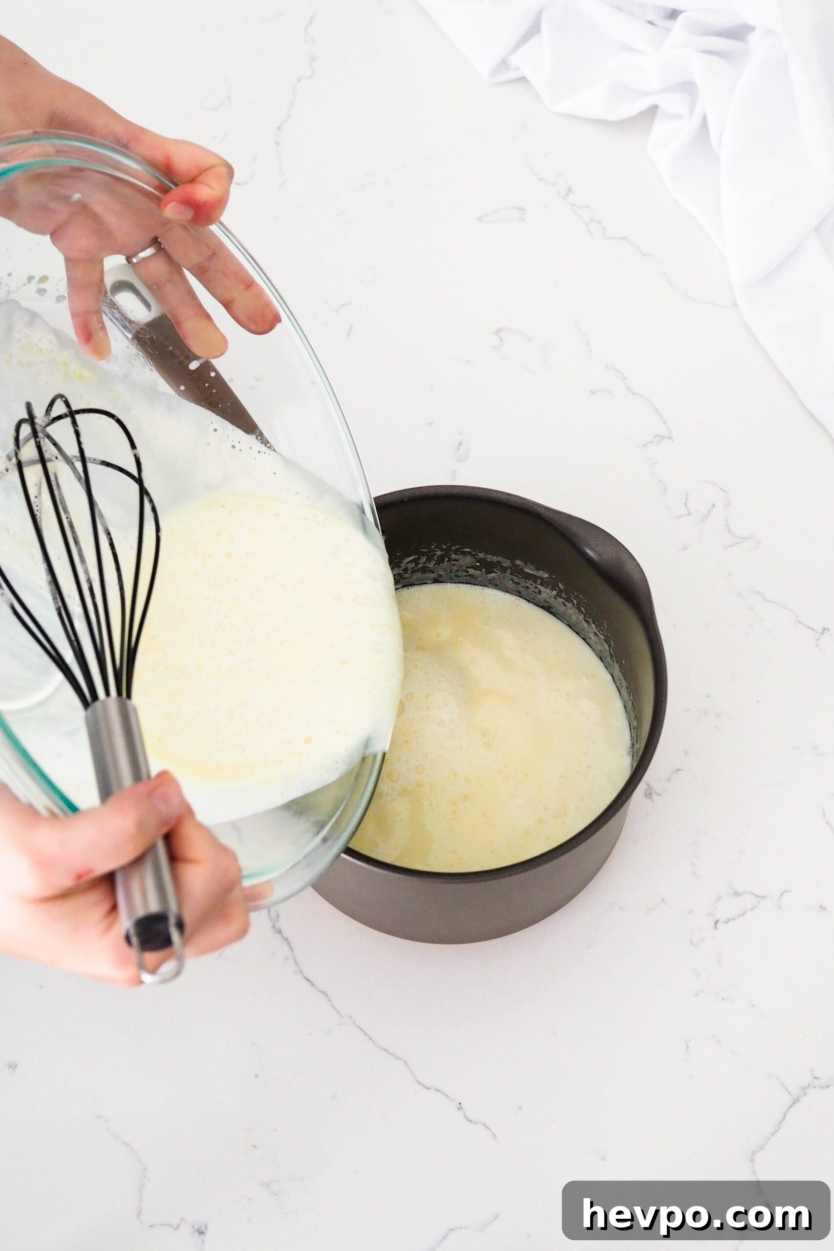 Homemade French Vanilla Ice Cream Recipe – Creamy & Classic 7 Two hands pour fresh custard back into a pot.