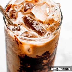 ice floating on top of coffee in a drinking glass
