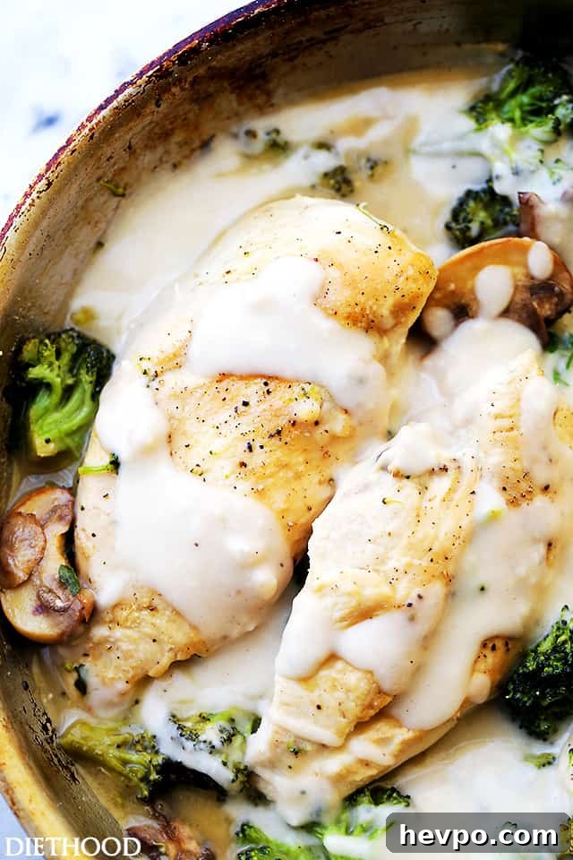 A close up of creamy chicken Alfredo with broccoli in a skillet.