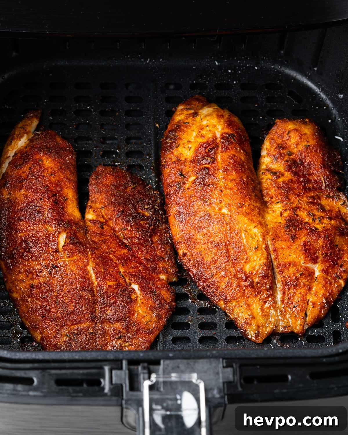 air fryer basket with blackened tilapia.