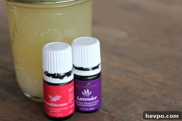 Image shows a jar of handmade soap with two bottles of essential oils in front on a table. 