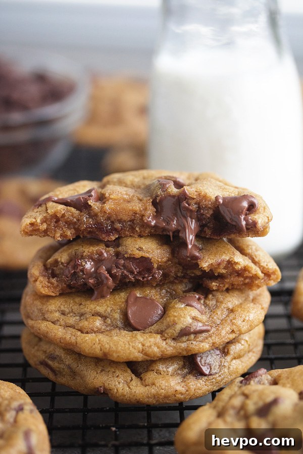 stack of browned butter chewy pumpkin chocolate chip cookies with the top one broken in half showing melty chocolate chips