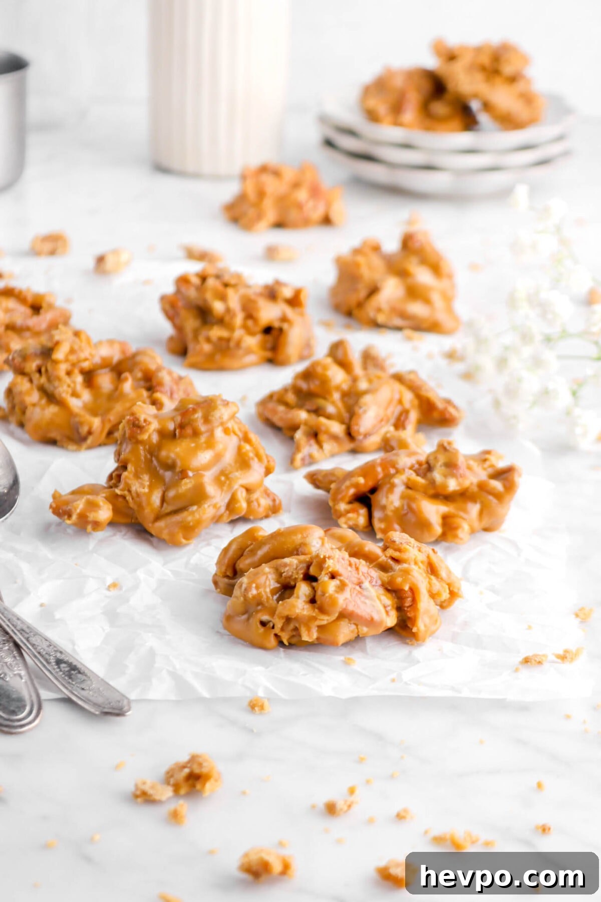 Southern Buttermilk Pecan Pralines Recipe – Classic Southern Candy 6 front shot of pecan pralines on parchment paper with flowers and stack of plates behind