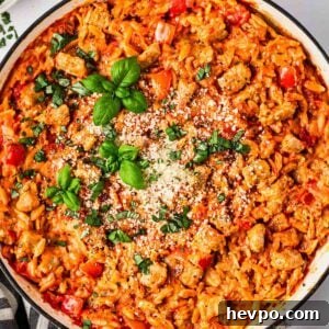 One-Pot Sausage and Orzo Dinner 9 A close look at one pot sausage orzo pasta dish in pan with basil and parmesan on top.