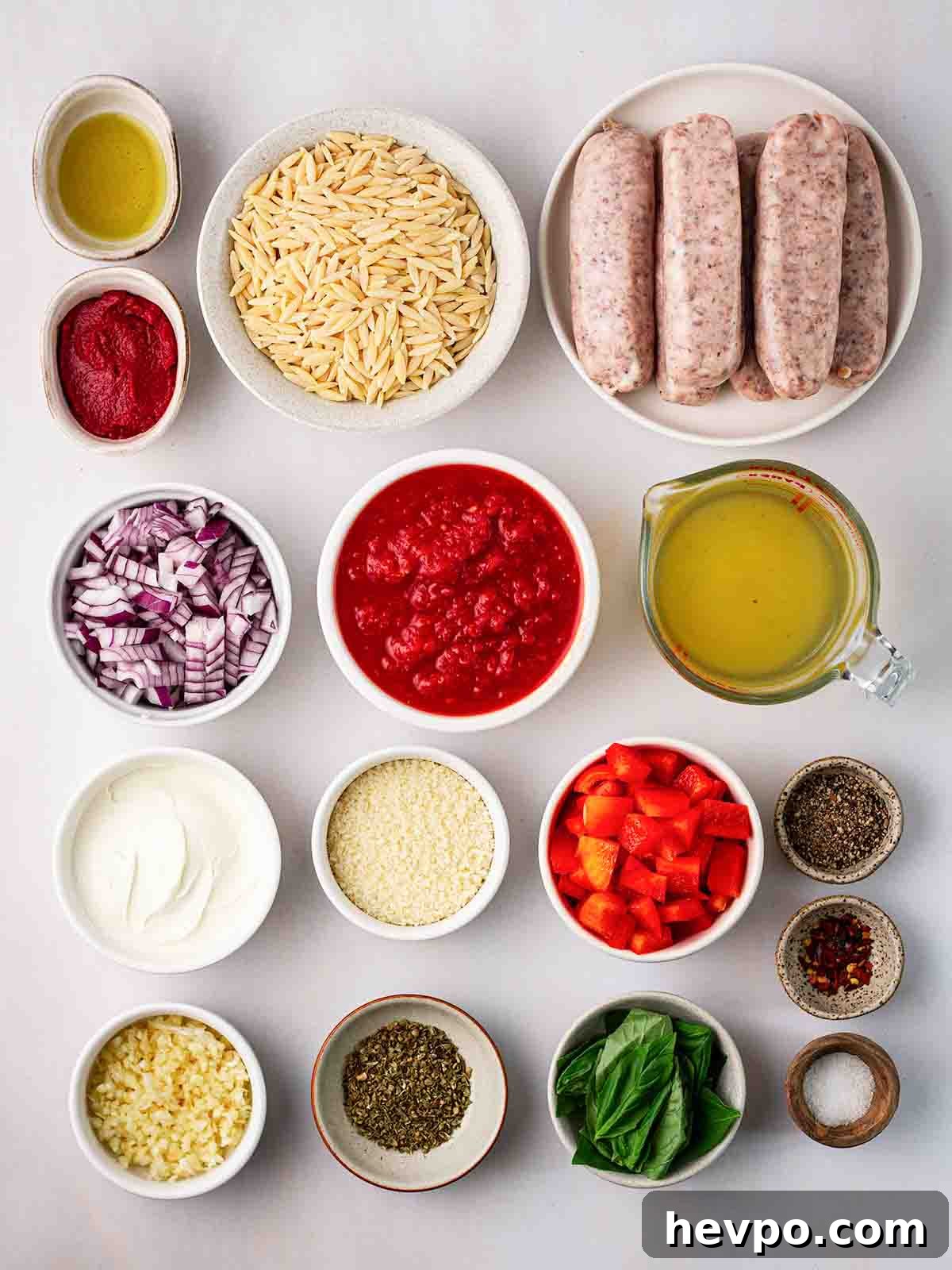 One-Pot Sausage and Orzo Dinner 4 Ingredients laid out on a counter top in small bowls. including sausages and orzo pasta and spices.