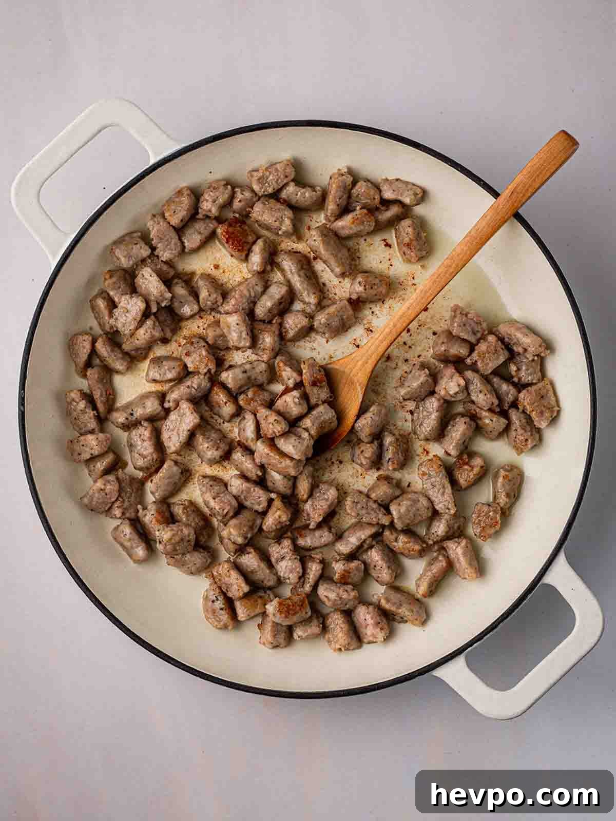 One-Pot Sausage and Orzo Dinner 5 A pan filled with chunks of sausage, browning in oil.