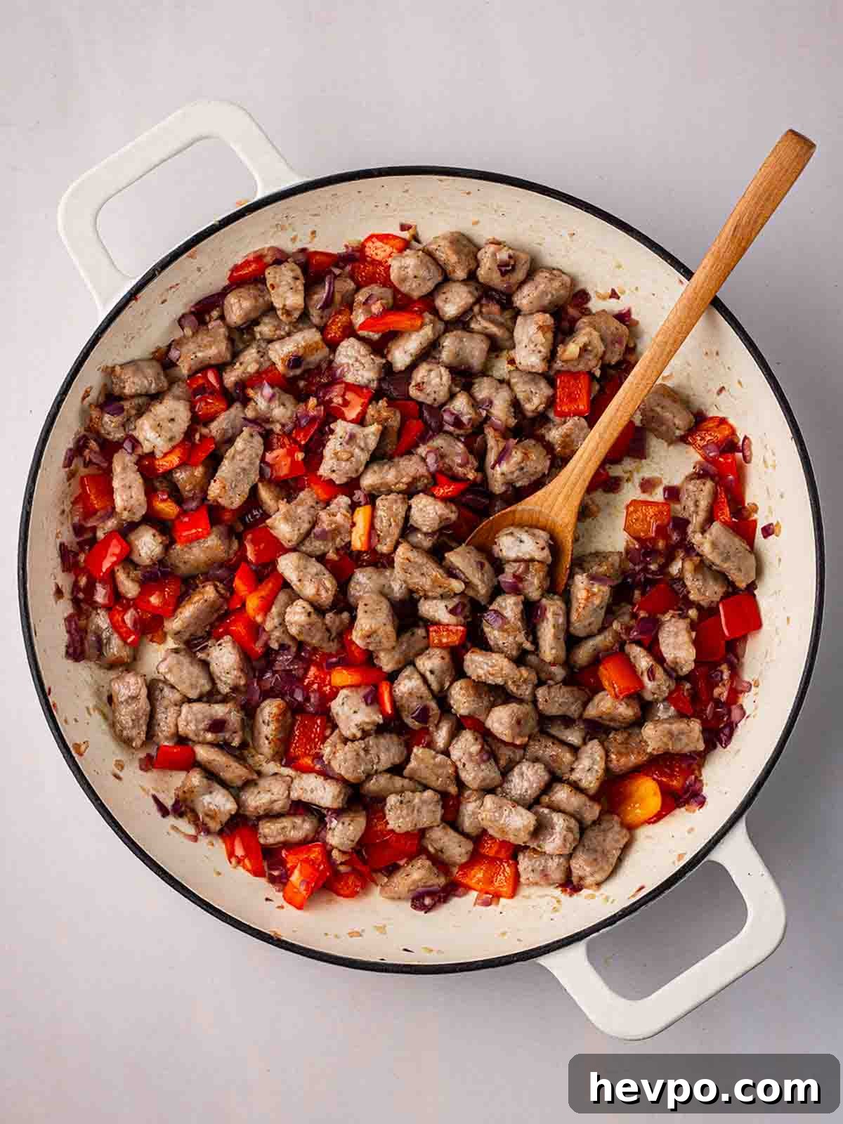 One-Pot Sausage and Orzo Dinner 6 Chucks of cooked sausage with red pepper cooking in a pan.