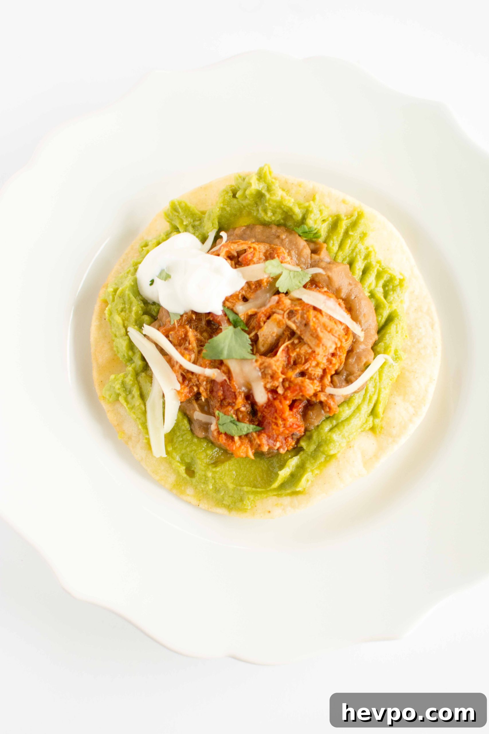 one chicken tinga tostada with dollop of sour cream