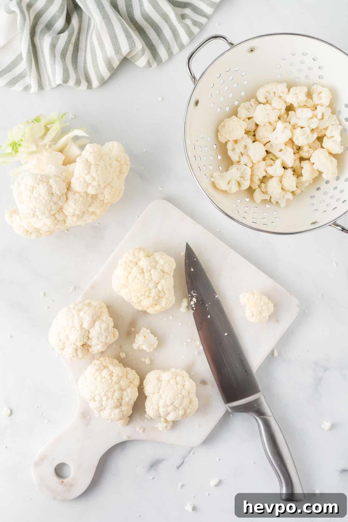 cutting board with cauliflower being cut with a knife