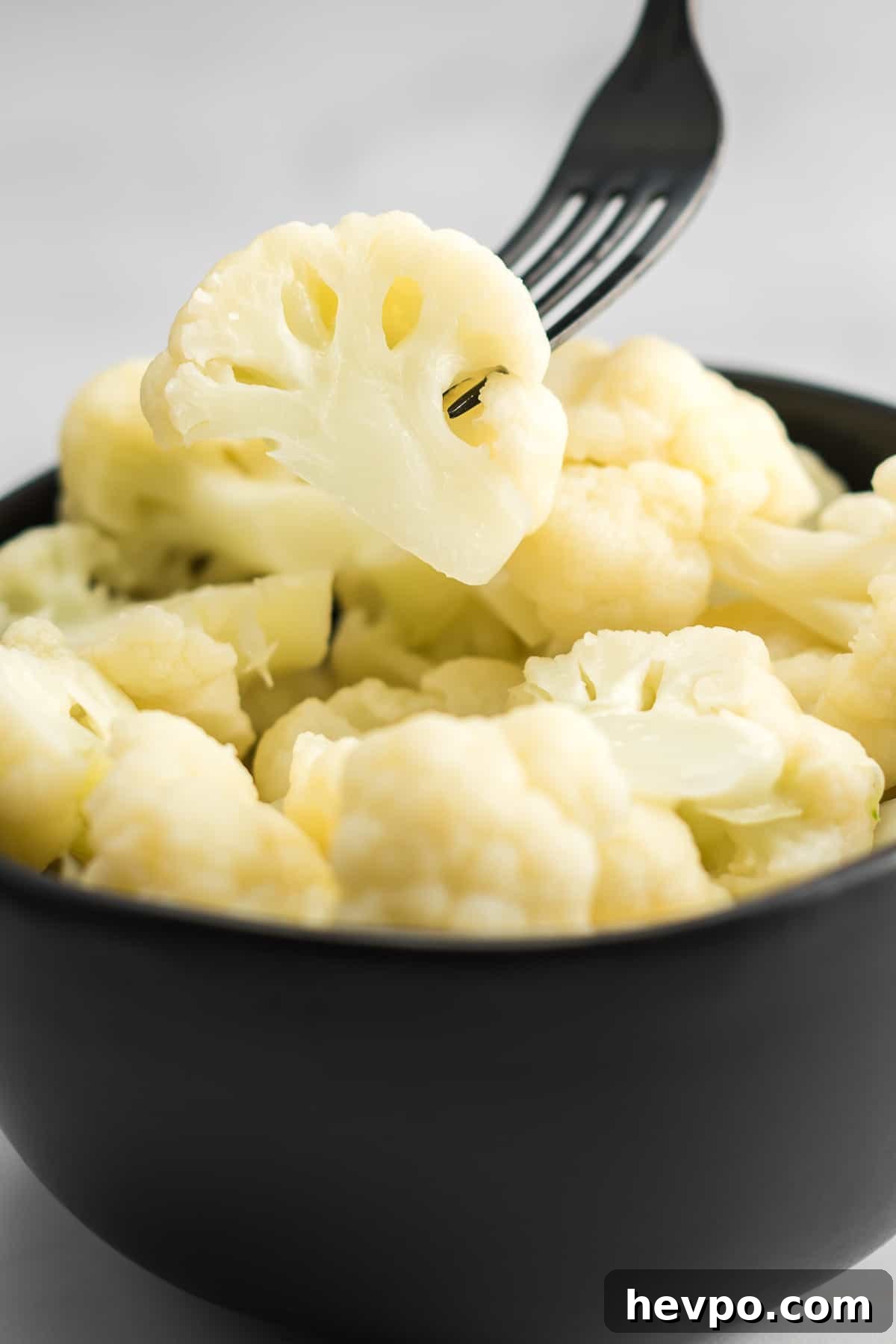 fork taking a floret of cauliflower from a bowl