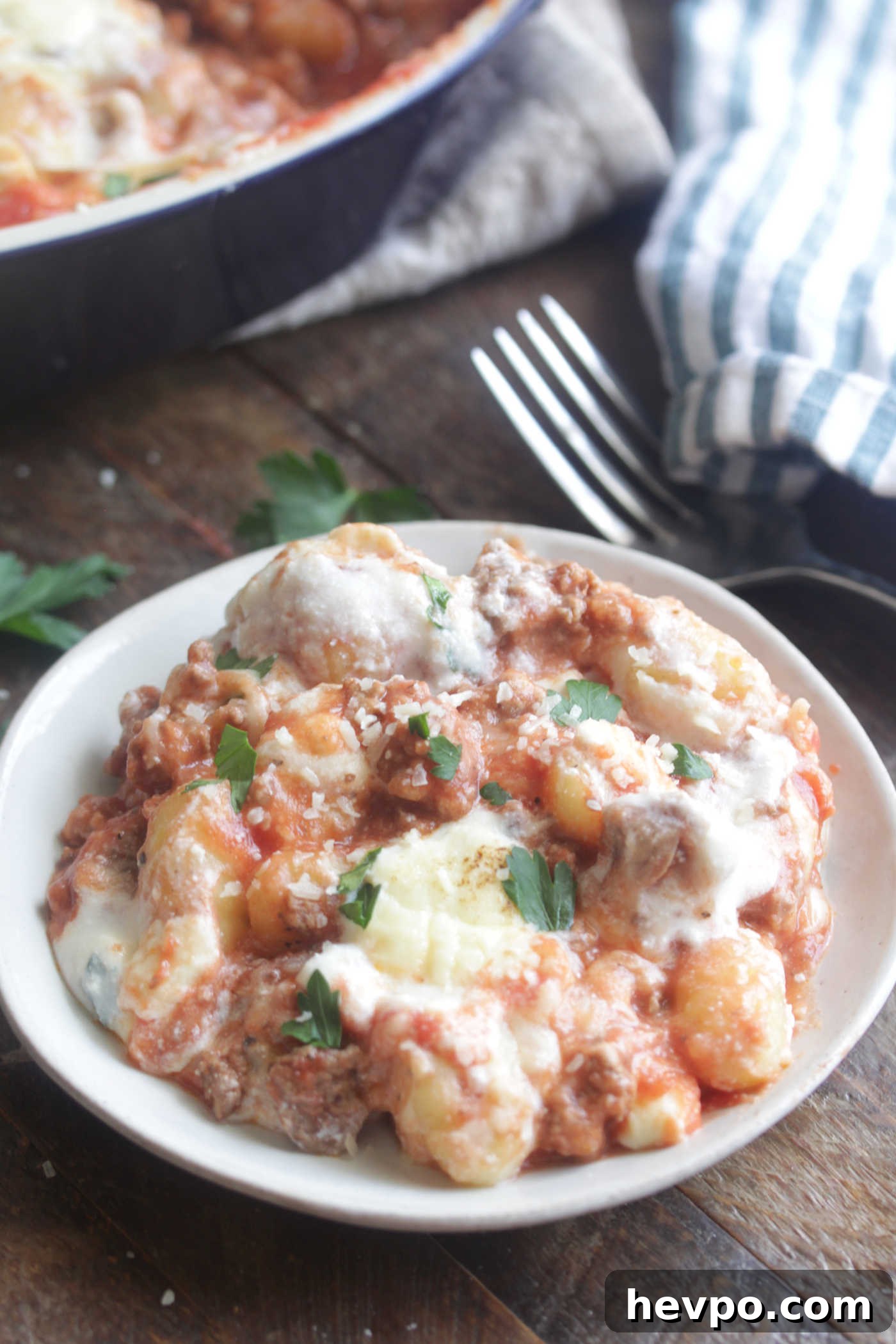 Angled photo of Gnocchi Lasagna Bake on a white dish with chopped parsley on top