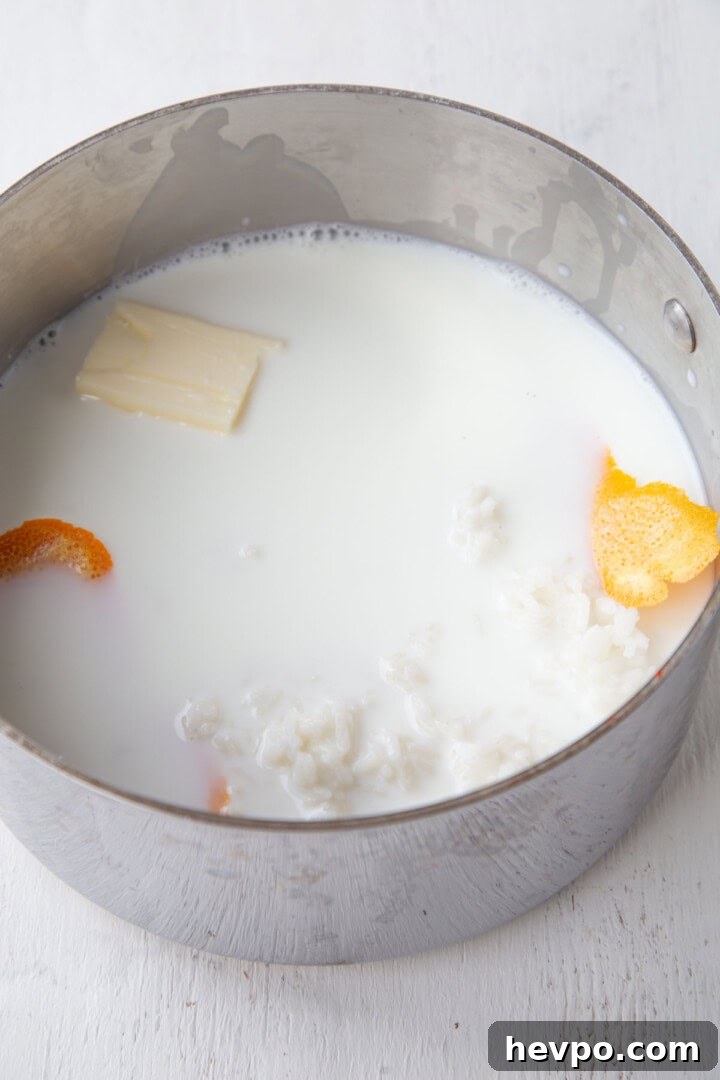Creamy Rice Pudding Made with Cooked Rice 5 milk, butter, rice, and orange peel in a saucepan.