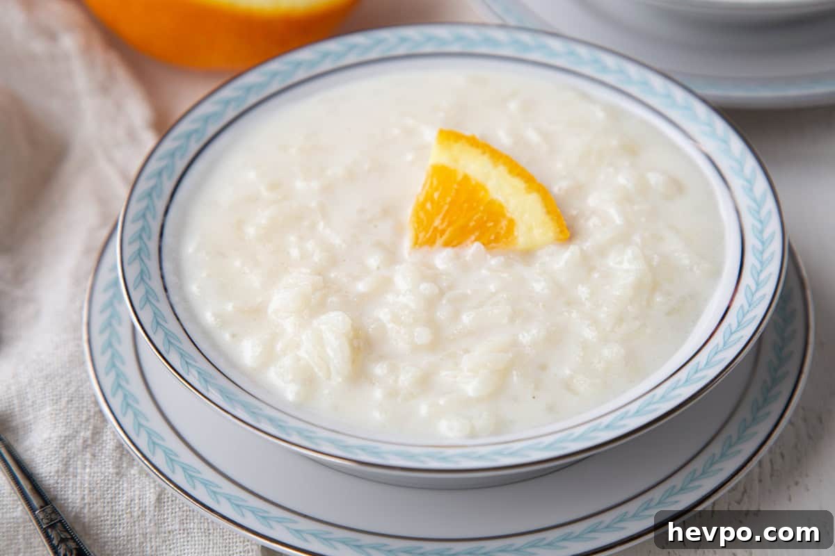 Creamy Rice Pudding Made with Cooked Rice 9 bowl full of creamy rice pudding with an orange slice garnish.