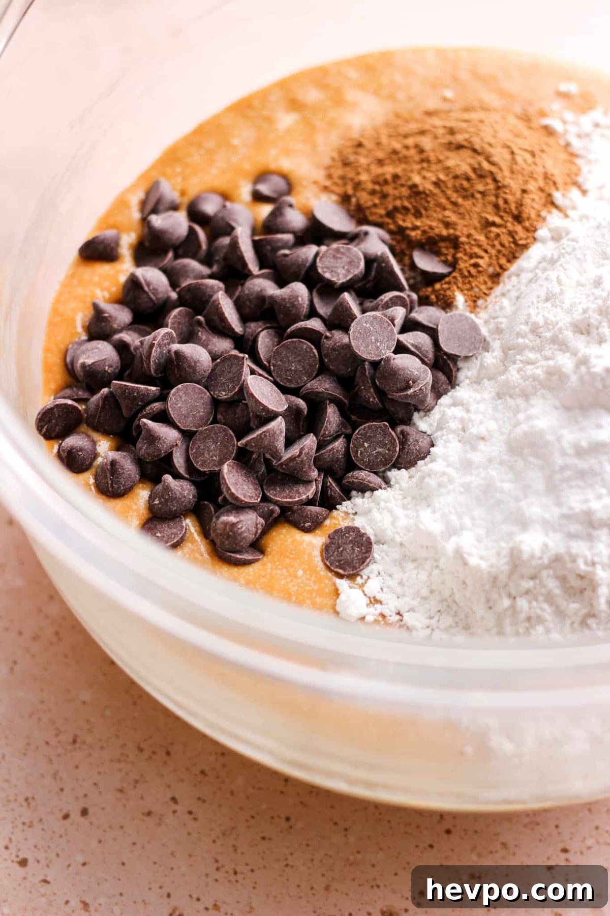 close up of chocolate chips and pumpkin bread ingredients in a glass mixing bowl