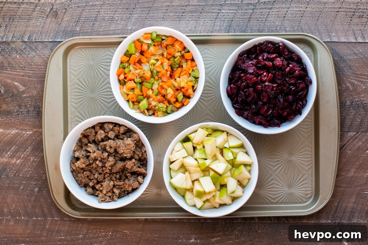 cooked sausage, cooked vegetables, dried cranberries, and sliced apple on tray