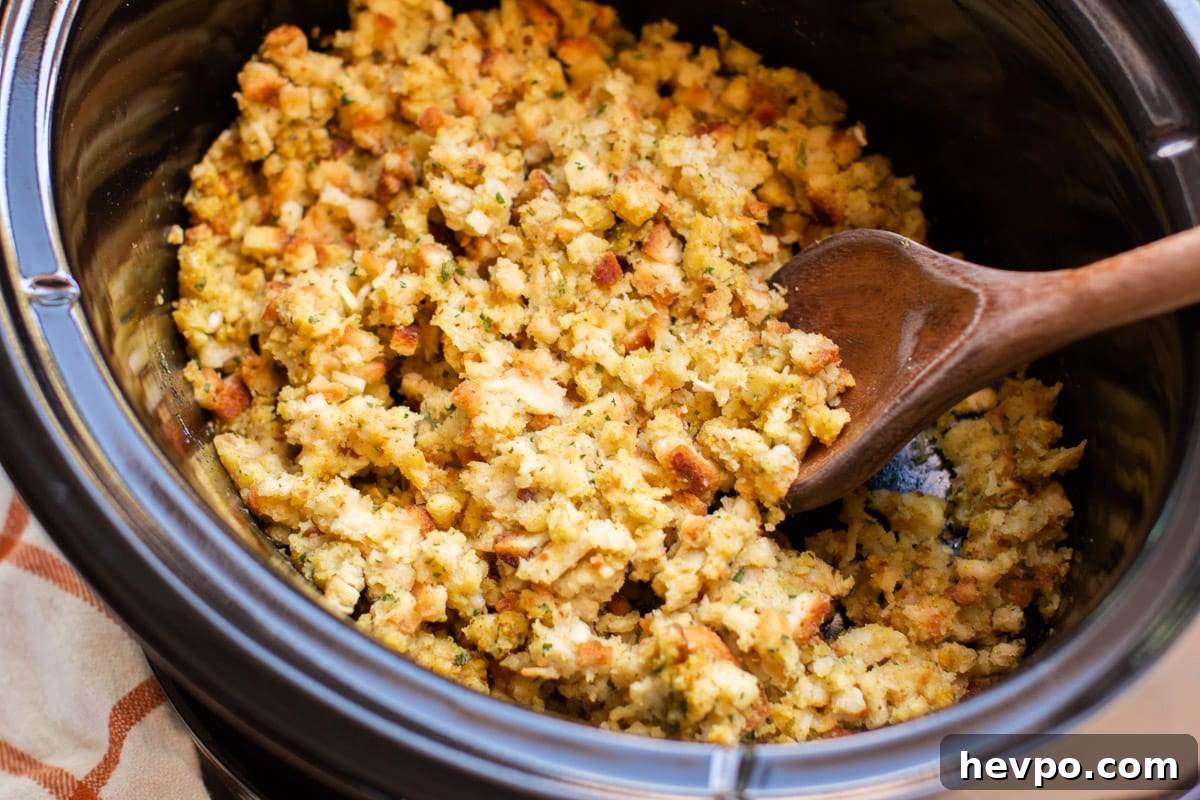 Close up of stove top stuffing in slow cooker with wooden spoon in it.