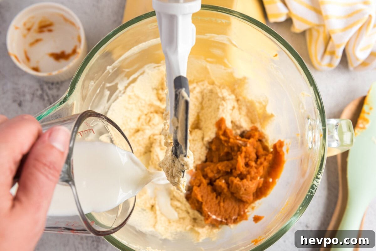 adding pumpkin puree and buttermilk to butter mixture in a bowl for muffins
