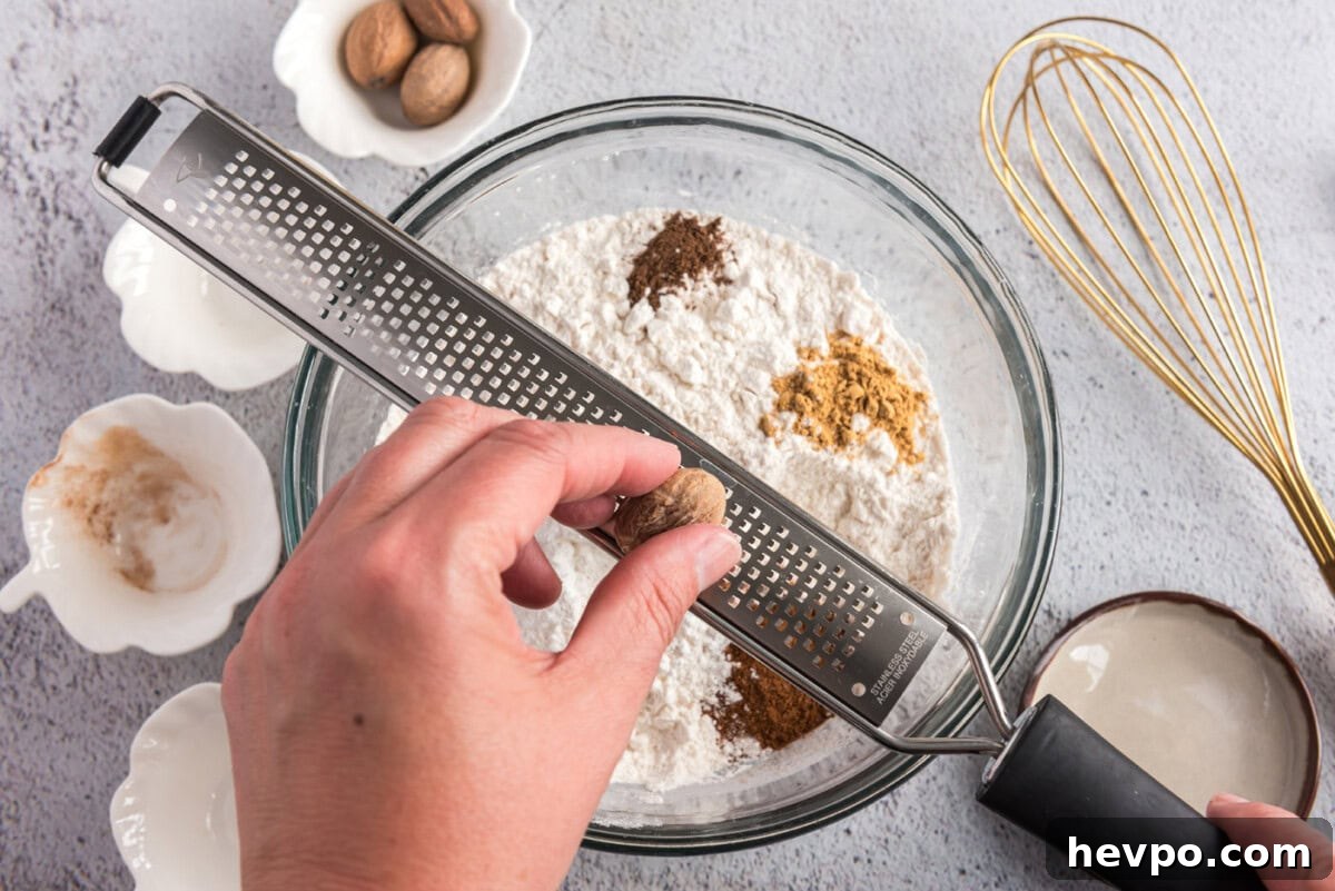 grating nutmeg over flour mixture and spices in a bowl