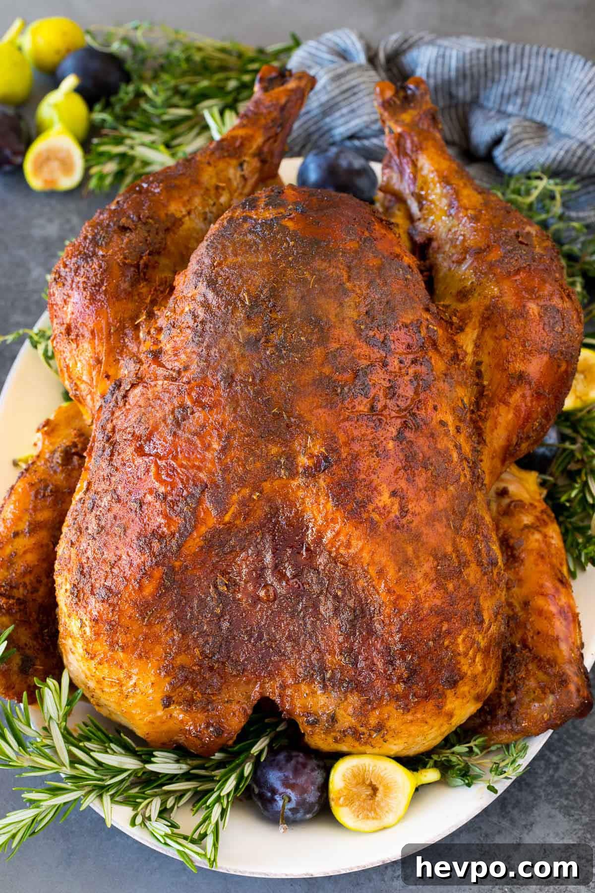 Cajun-Roasted Turkey Recipe for Bold, Spicy Flavor 2 A Cajun turkey on a serving platter garnished with fruit and herbs.