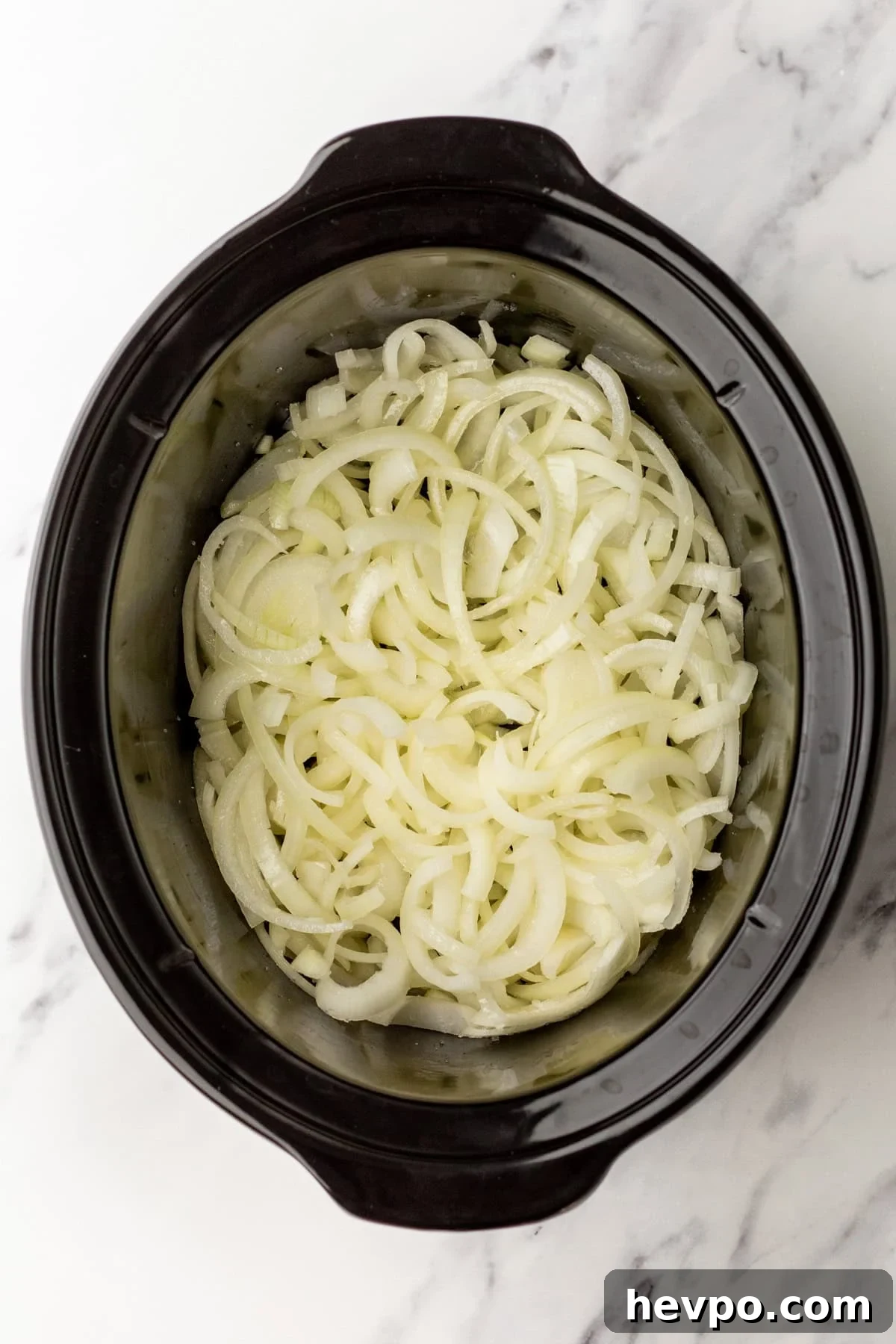 Slow Cooker Caramelized Onions Recipe for Sweet, Hands-Off Flavor 3 An overhead image of onions in a slow cooker.