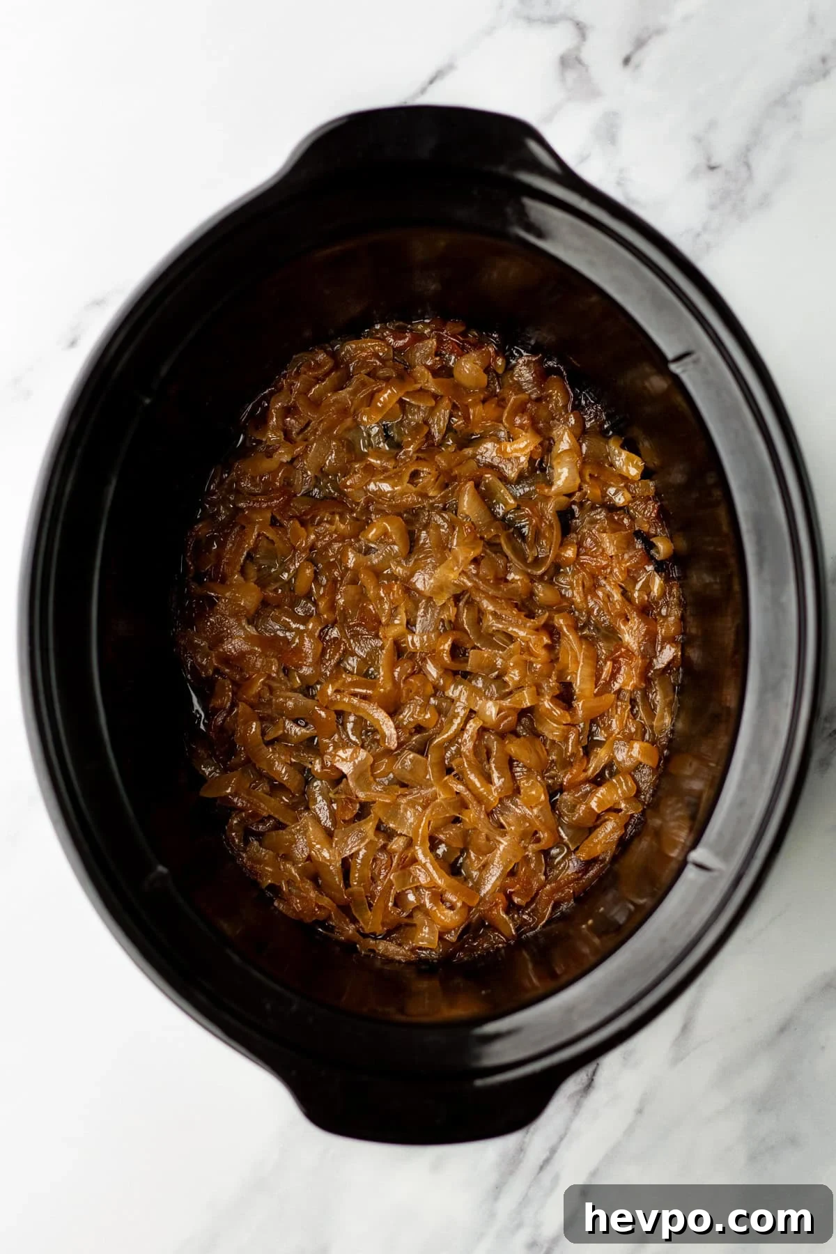 Slow Cooker Caramelized Onions Recipe for Sweet, Hands-Off Flavor 4 An overhead image of the caramelized onions in the slow cooker.