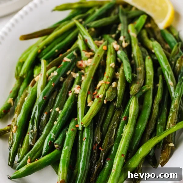 Slow Cooker Caramelized Onions Recipe for Sweet, Hands-Off Flavor 9 Close-up of skillet green beans with garlic, red pepper flakes, and lemon wedges on a serving platter.