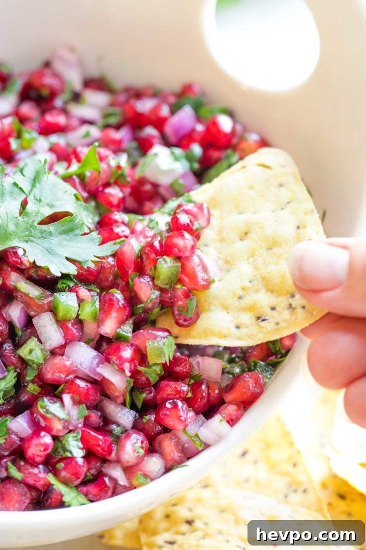 Tortilla chip dipping into pomegranate salsa