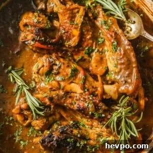 up close photo of smothered turkey wings in a pot garnished with rosemary.