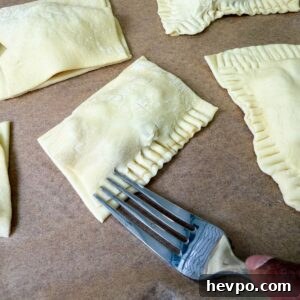 Classic Apple Hand Pies Made with Flaky Puff Pastry 9 Fork crimping apple hand pie edges.
