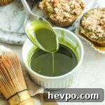 Spoon pouring matcha vanilla bean glaze for cakes, muffins, quick breads, and more in a white ceramic ramekin.