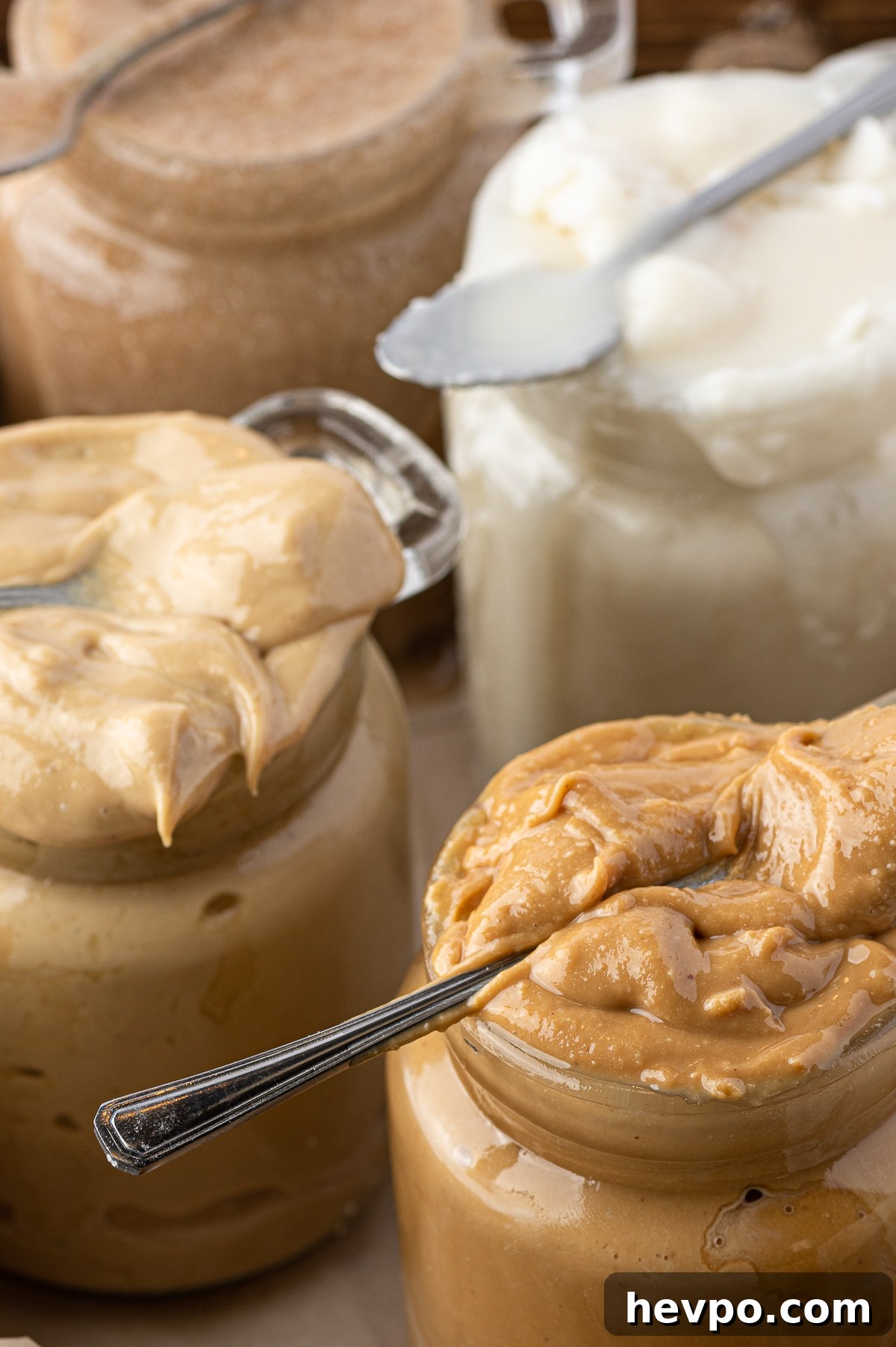Jars of different nut butters overflowing from their glass jars