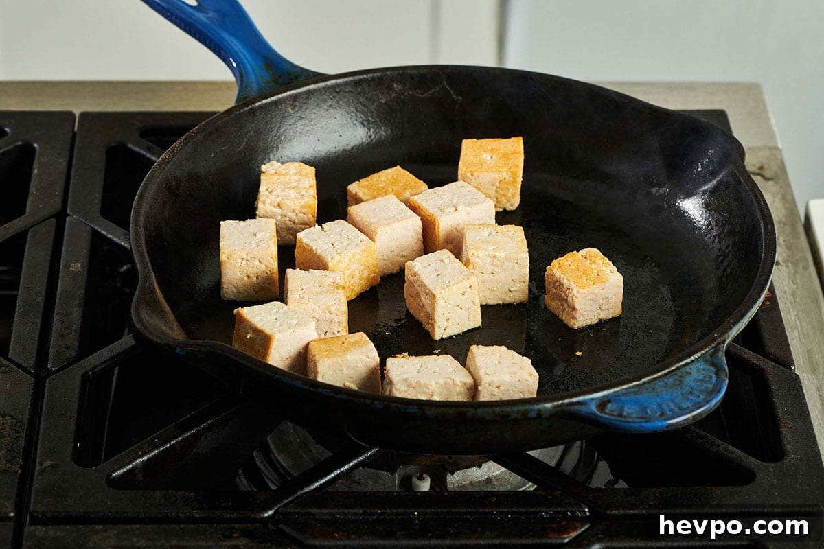 How to Press Tofu for Firmer, Crispier Results 9 Cooking cubed tofu in pan on stove.