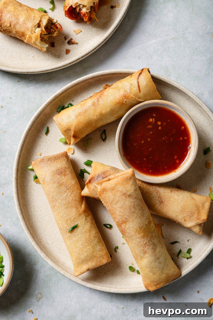 Chicken Spring Rolls on a round plate with a small bowl of dipping sauce ready to be eaten.