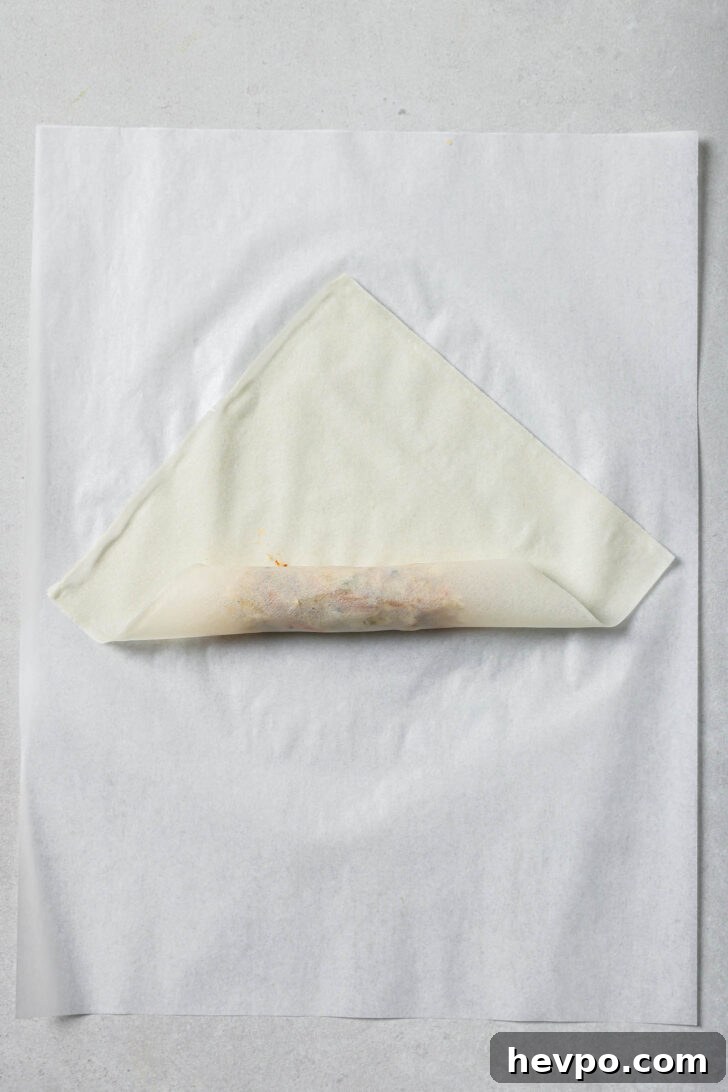 Bottom corner of spring roll wrapper rolled up and over the filling.