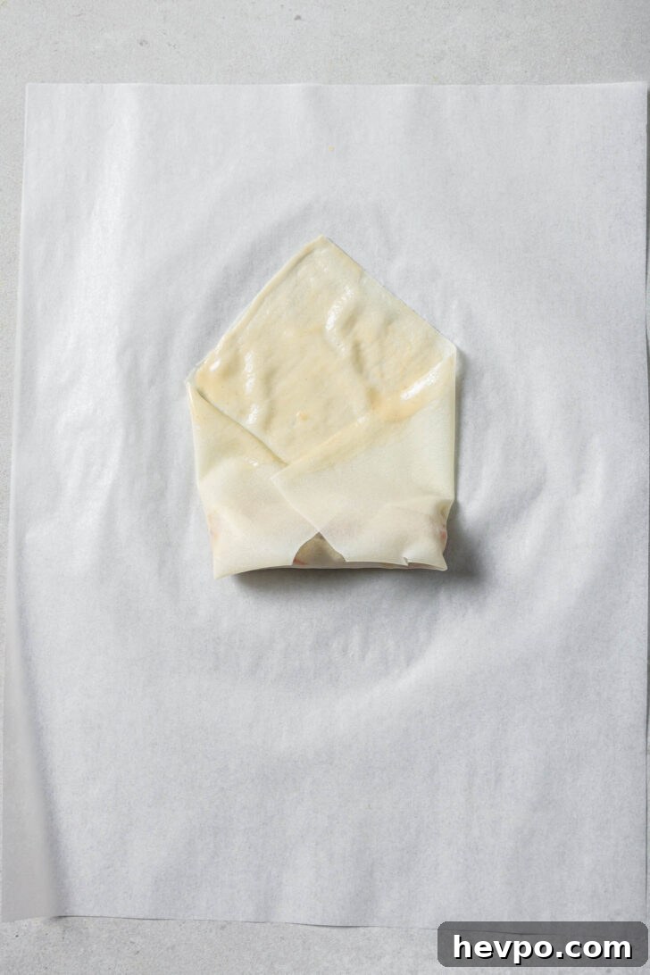 Sides of spring roll wrapper folded to toward centre over the filling.