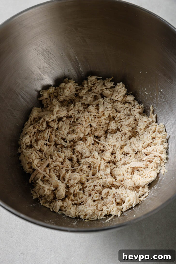 Shredded chicken in a bowl for making Chicken Spring Rolls.