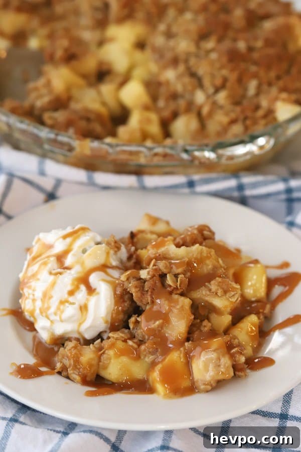 Caramel Apple Crisp with Crunchy Oat Topping Recipe 2 Caramel Apple Crisp with Oat Topping on a white serving place, topped with whipped cream.