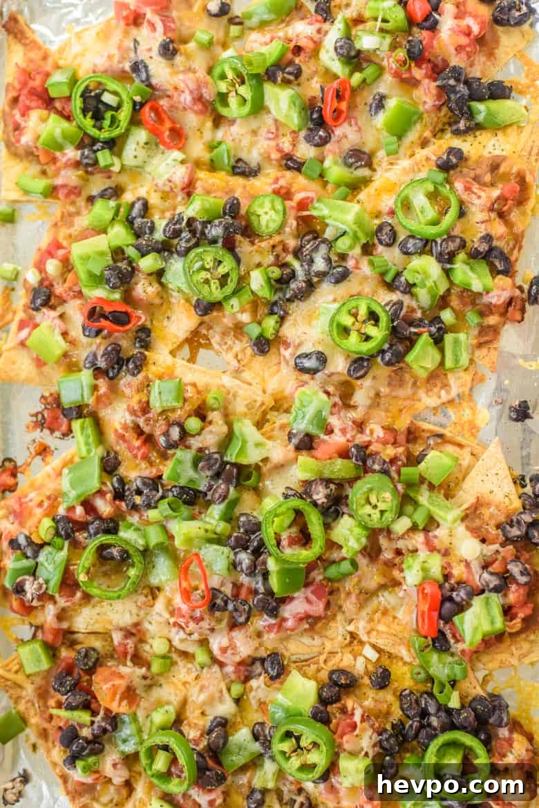 Sheet pan nachos with refried beans, black beans, salsa, cheese, jalapeños, and chopped peppers