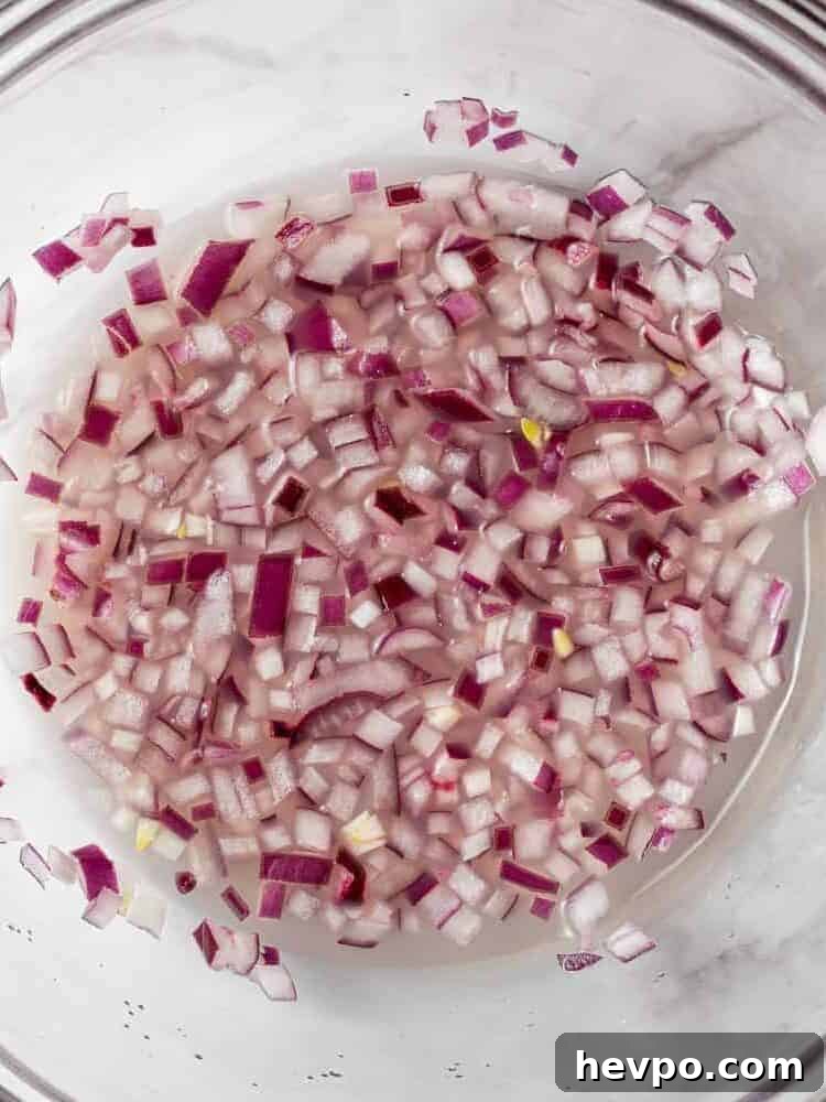 Onions in lime juice in a clear glass bowl.