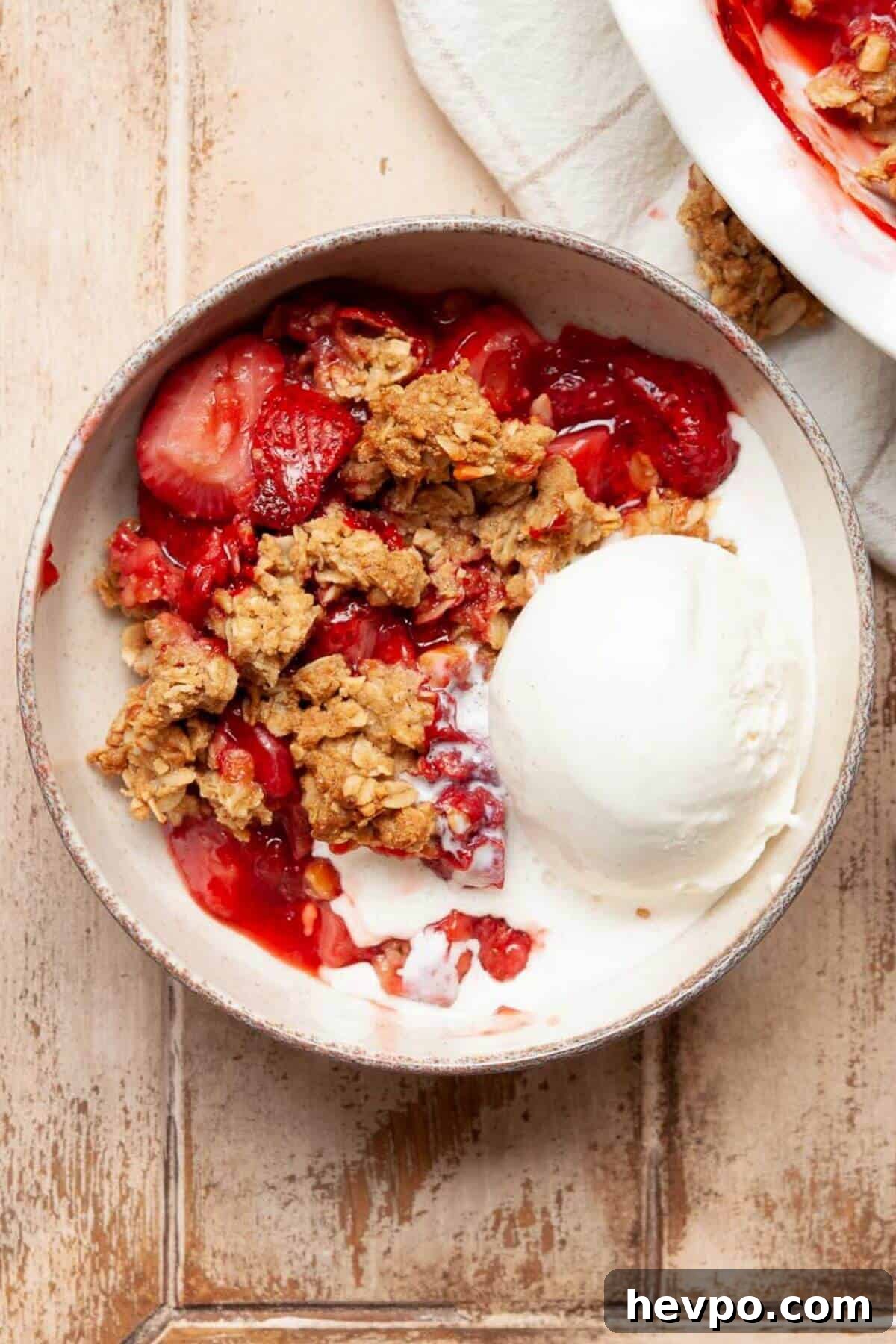 Strawberry Crumble with Oat Topping Recipe 2 Healthy strawberry crumble served warm in a bowl with a scoop of vanilla ice cream melting on top.