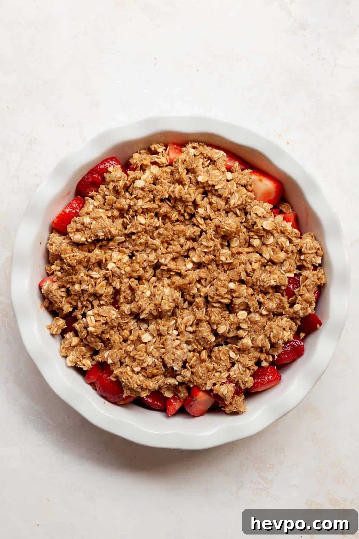 Strawberry Crumble with Oat Topping Recipe 7 Unbaked strawberry crumble with oat topping spread evenly over fresh strawberries in a pie dish.
