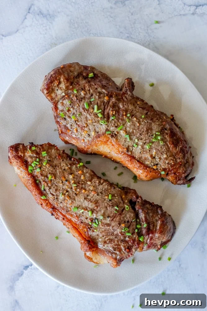 picture of two steaks on a white plate with chives 