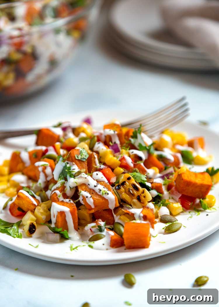 This healthy Sweet Potato and Corn Salad has roasted sweet potatoes and corn, bell peppers and pumpkins seeds tossed in a Mexican crema sauce with lime. Sweet Potato and Corn Salad on white plate
