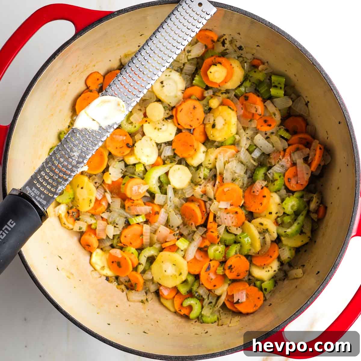 Autumn Vegan Minestrone: Hearty Fall Vegetable Soup 7 Grating garlic over a dutch oven with sauteed veggies.