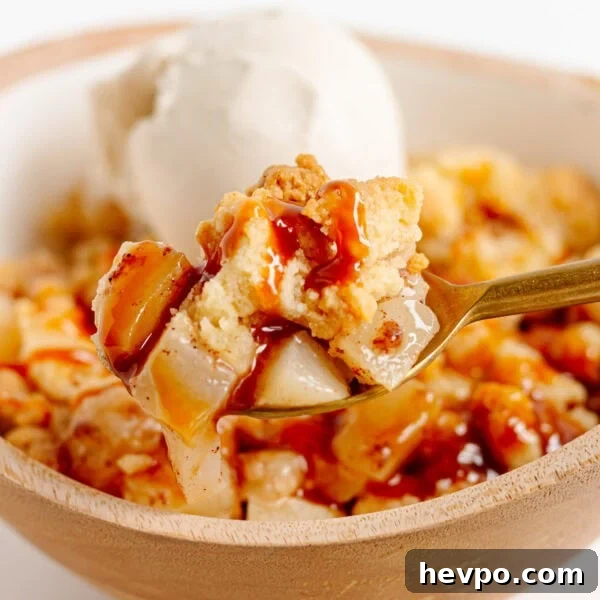 Spoonful of pear crumble being lifted from bowl.