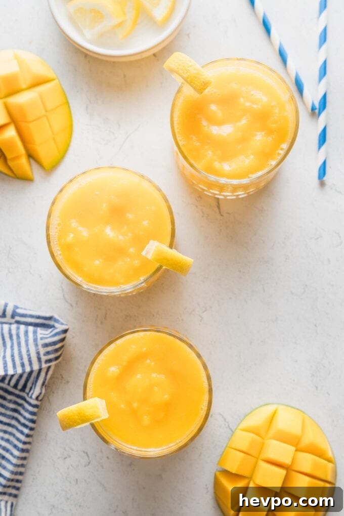 Countertop set with glasses of frozen mango lemonade.