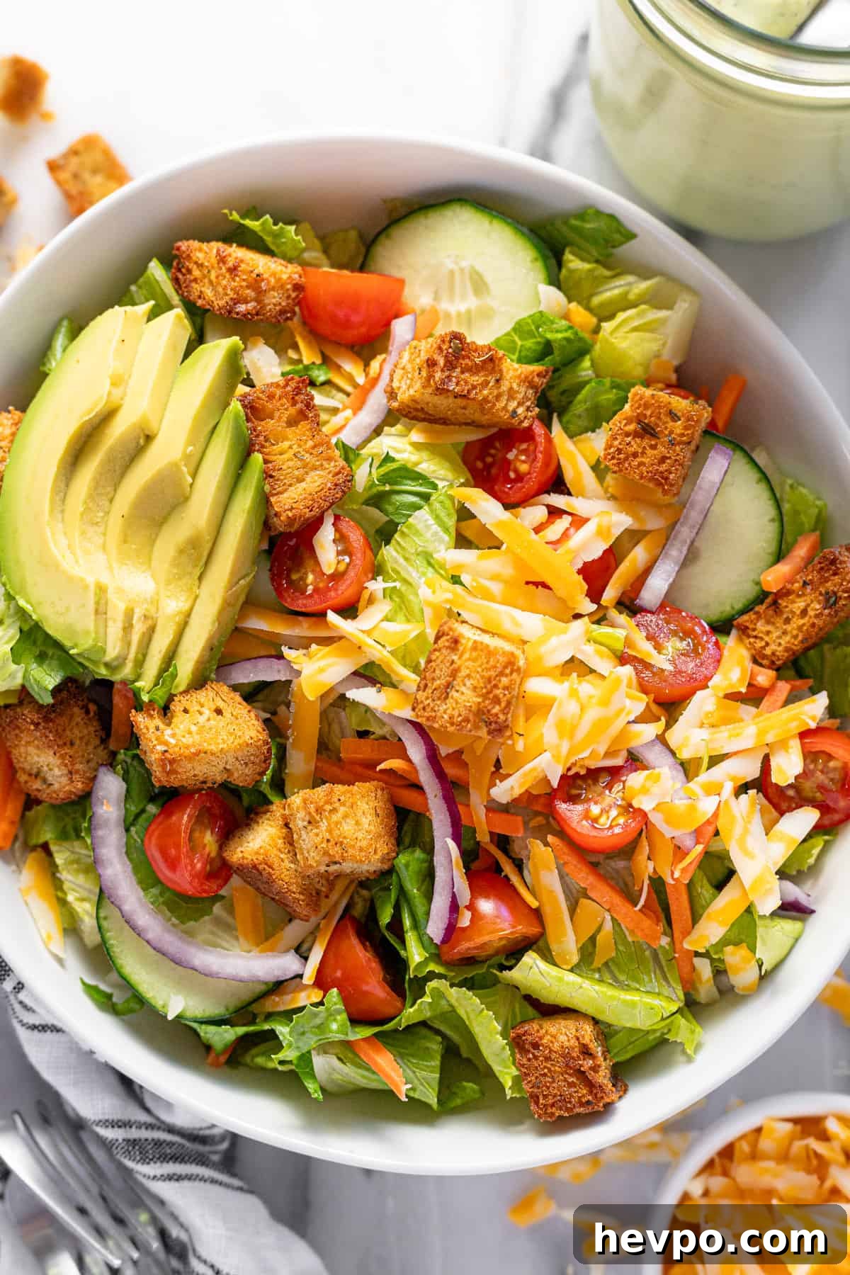Large bowl filled with house salad filled with veggies, cheese, and croutons.