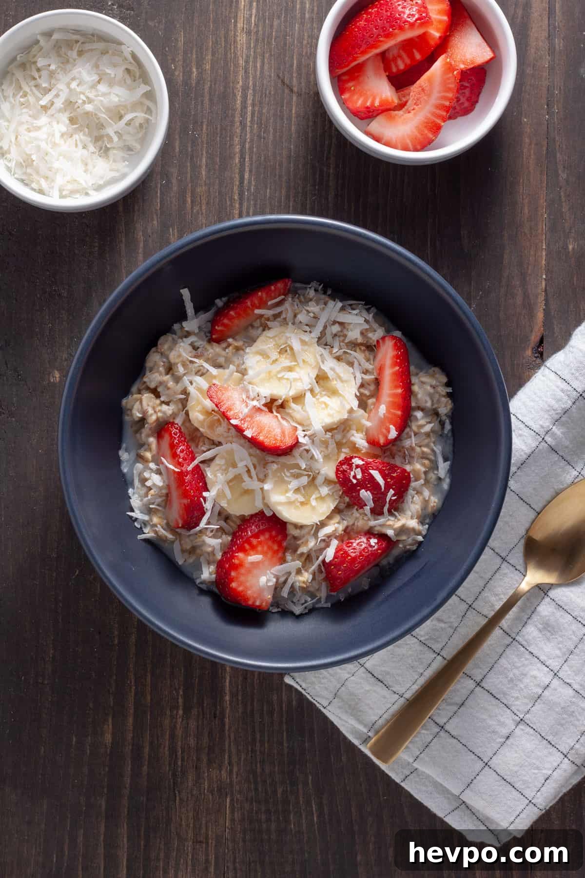Coconut Milk Overnight Oats Recipe for Creamy Breakfast 7 A serving of coconut overnight oats in a blue bowl topped with strawberries, shredded coconut and bananas.